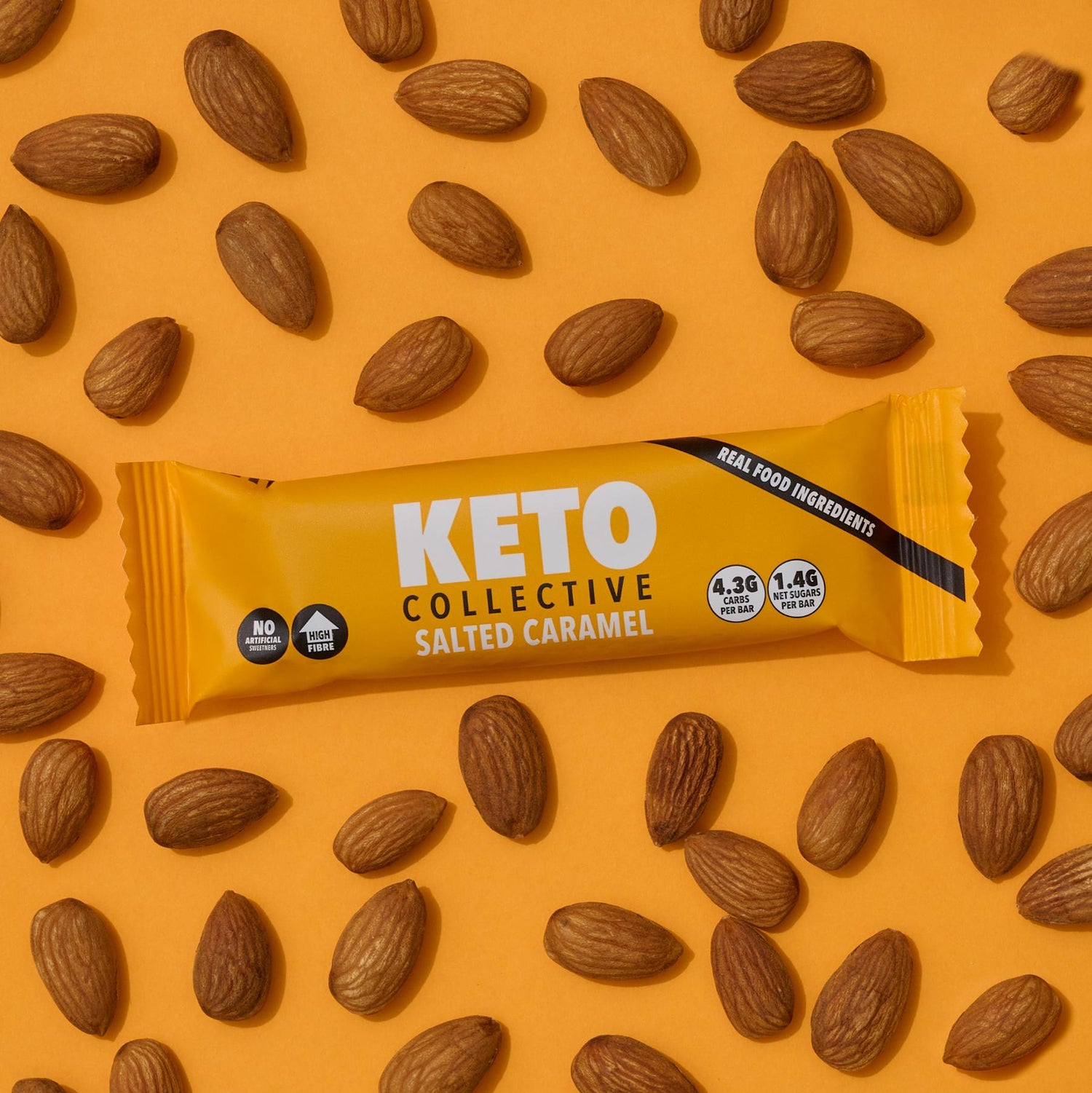 salted caramel keto bar and almonds orange background